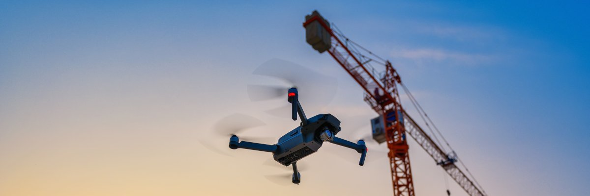 Titelbild: Eine Drohne fliegt neben einem Kran
